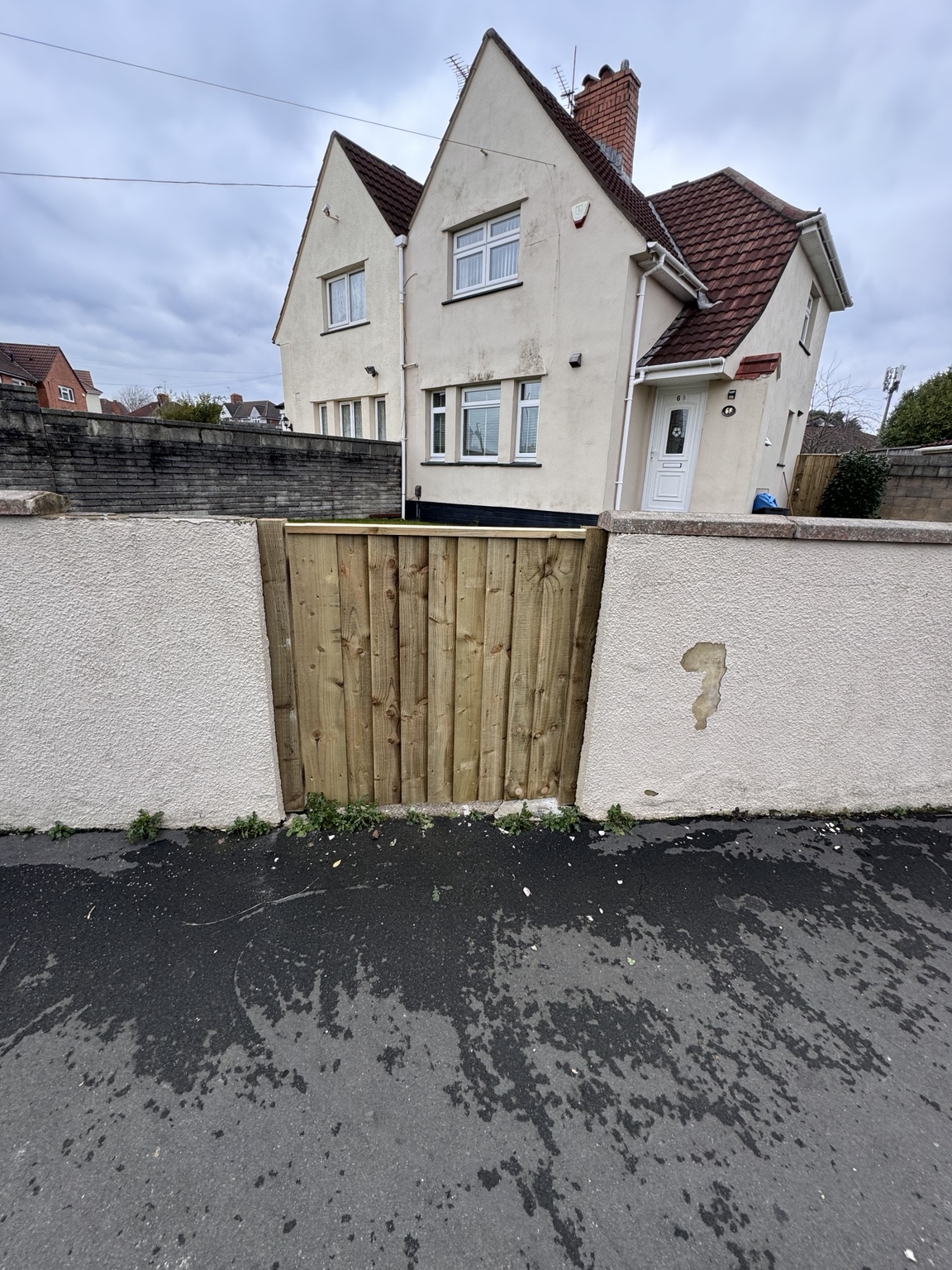 Timber side gate fitted into a rendered boundary wall